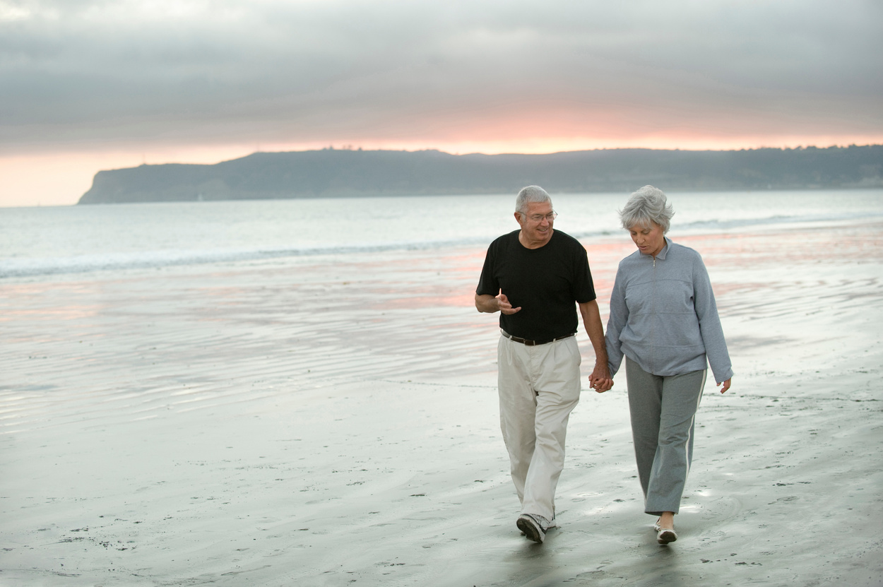 Senior couple out walking the beach at dusk