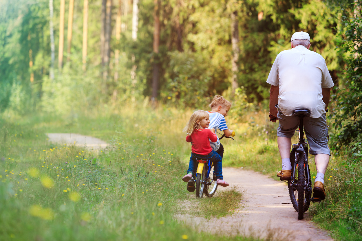active senior with grandkids riding bikes in nature, active retirement