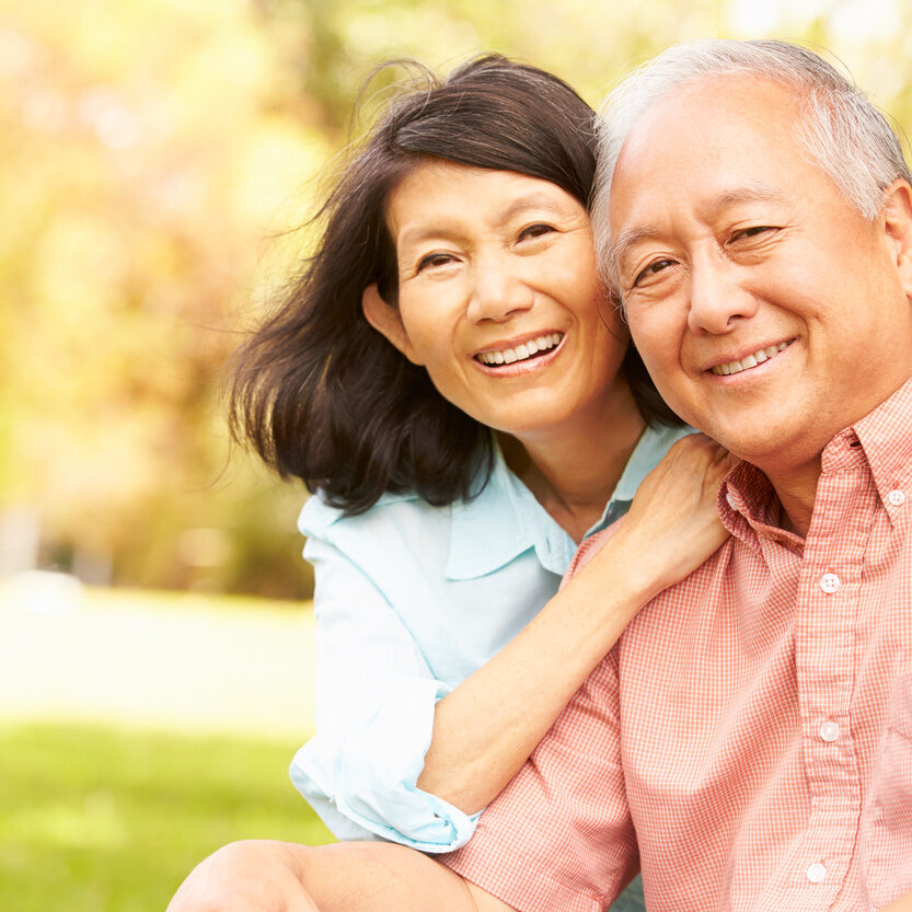 Portrait Of Senior Asian Couple Sitting In Park Together